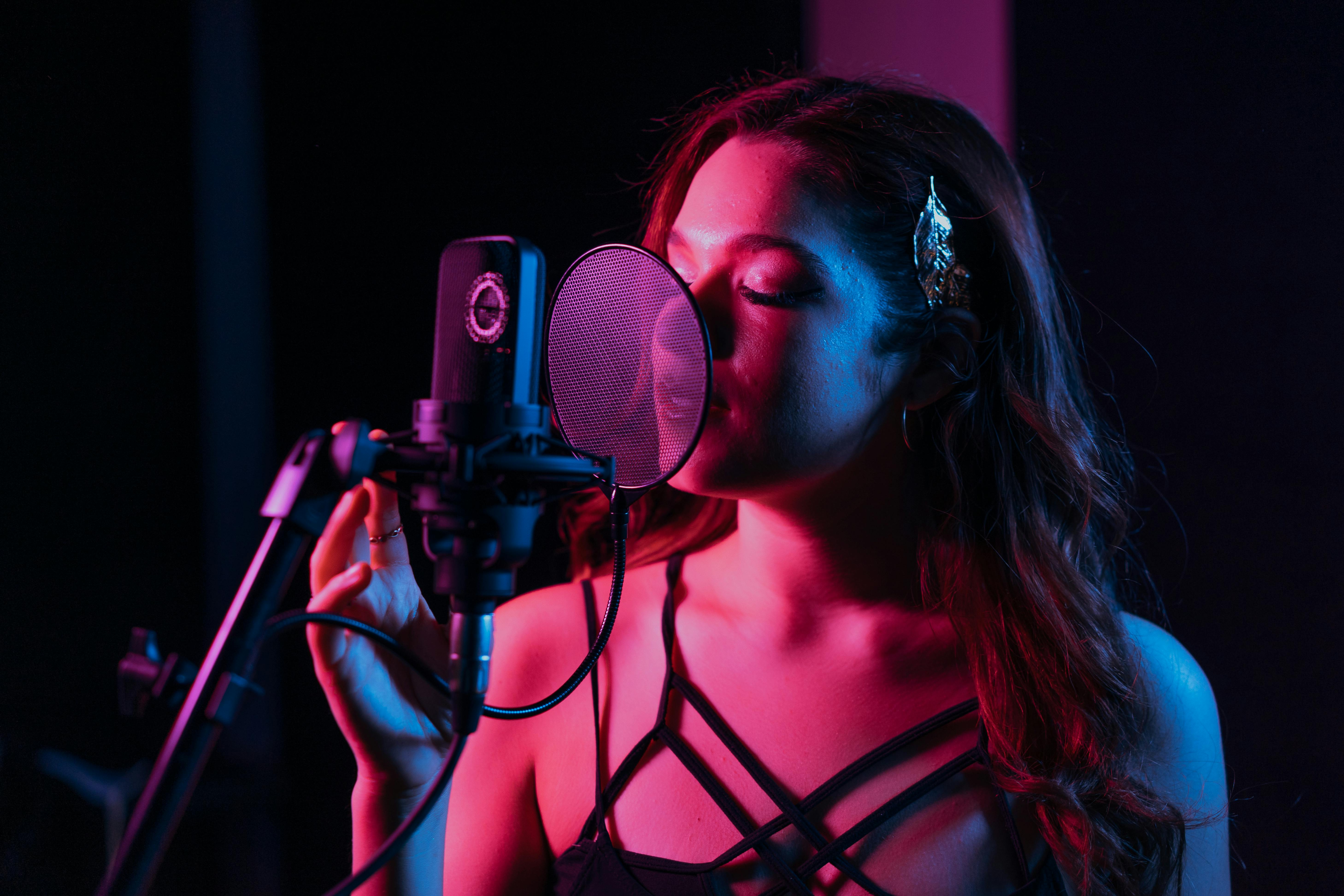 Femme chantant devant un micro en studio, en train de s’enregistrer.