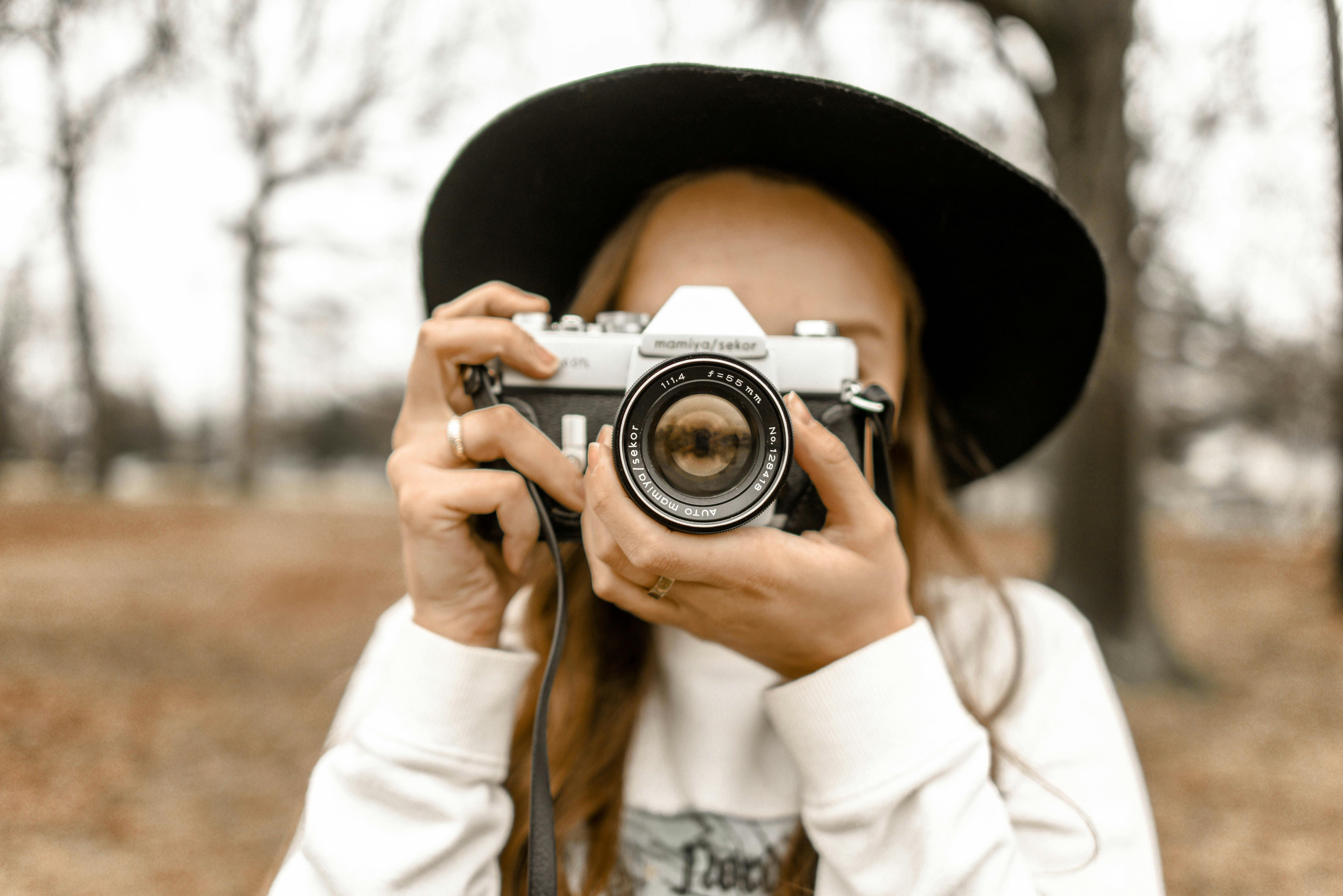 Femme regardant l’objectif, tenant un appareil photo devant elle, prête à capturer une image