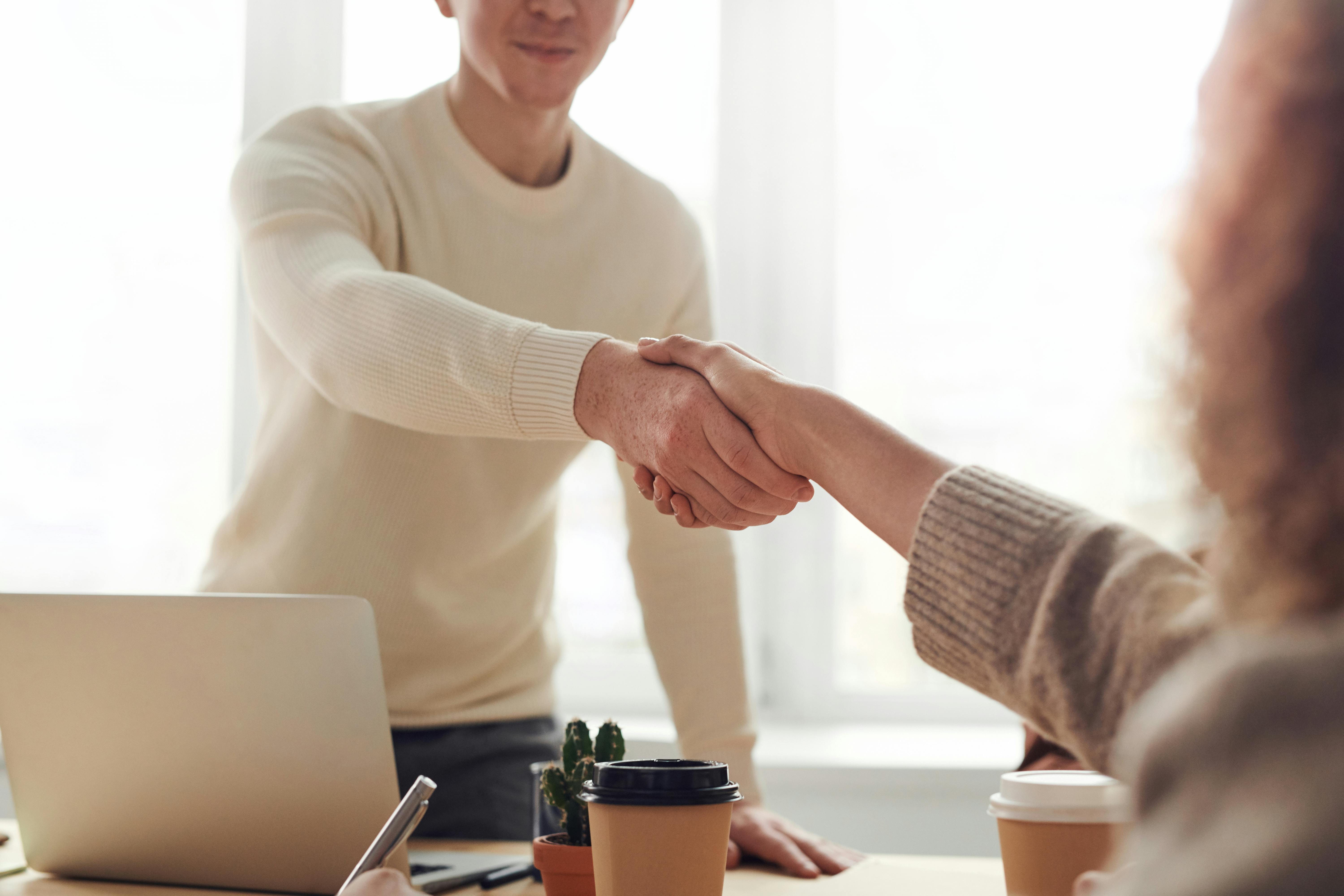 Un homme et une femme se serrent la main à un bureau