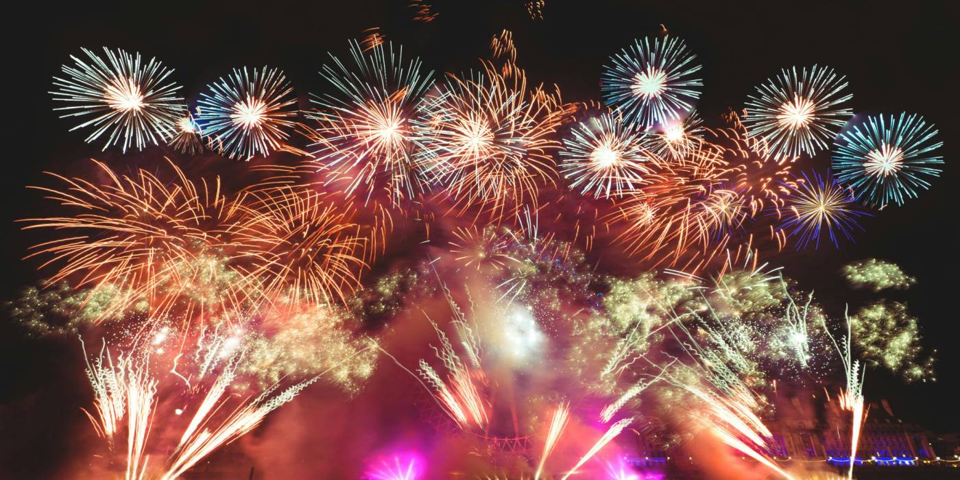 Feux d'artifice colorés illuminant le ciel nocturne au-dessus de l'eau calme