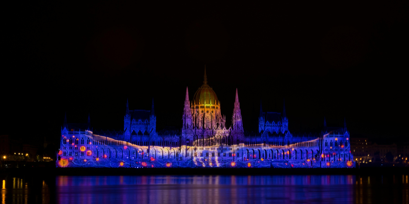 Projection de mapping vidéo sur la façade d’un bâtiment avec reflets lumineux sur l’eau environnante
