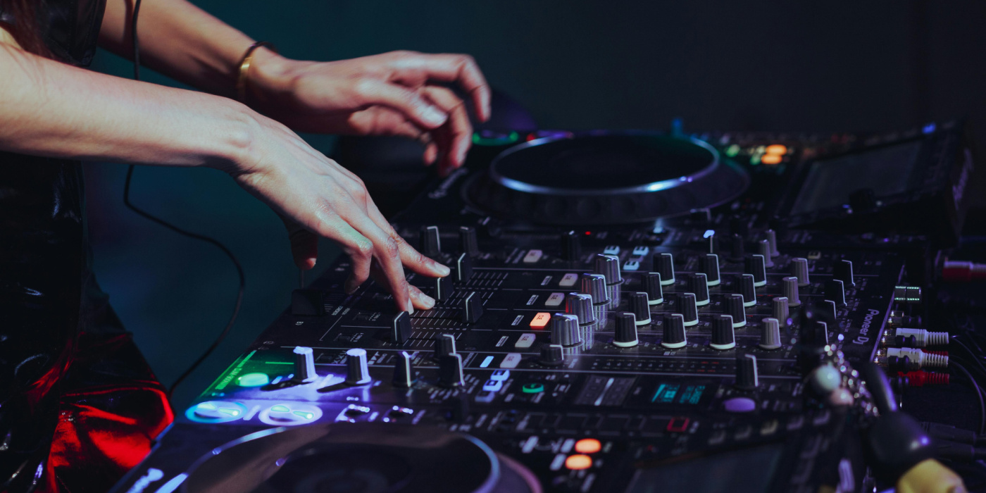 Main en train de manipuler les réglages d’une table de mixage audio professionnelle.