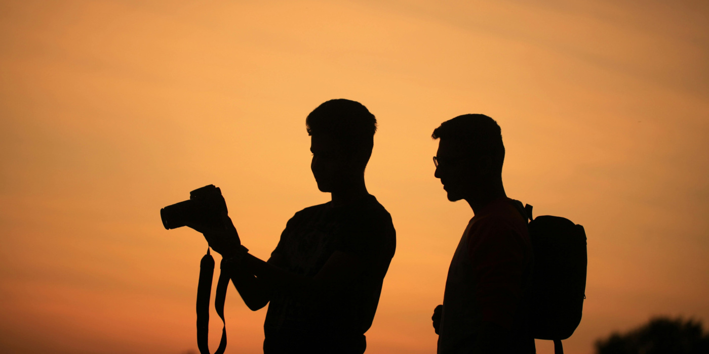 "Silhouettes d’un photographe et d’une personne côte à côte au coucher du soleil